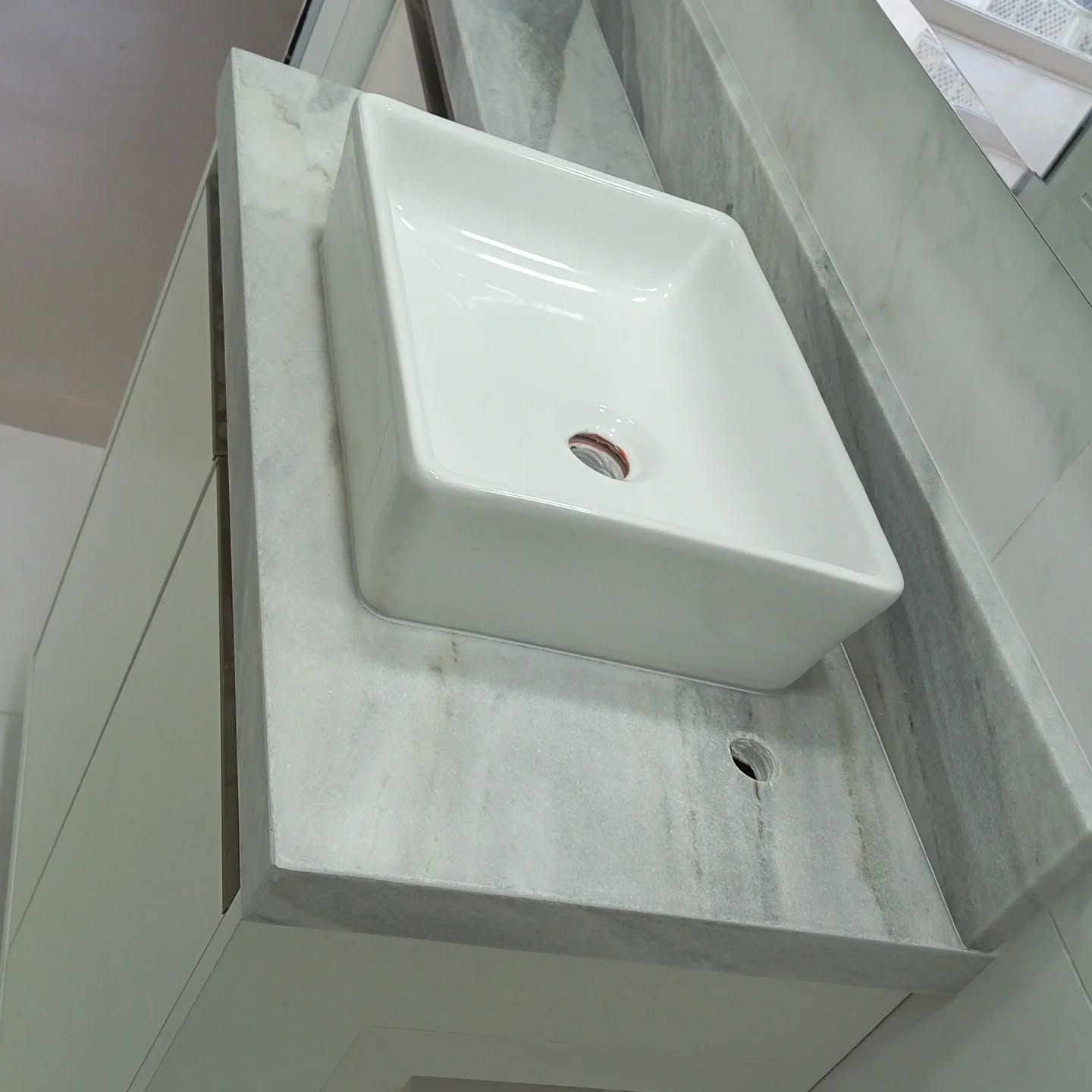 Lavabo com cuba de apoio branca sobre bancada de mármore cinza executado pela BSG