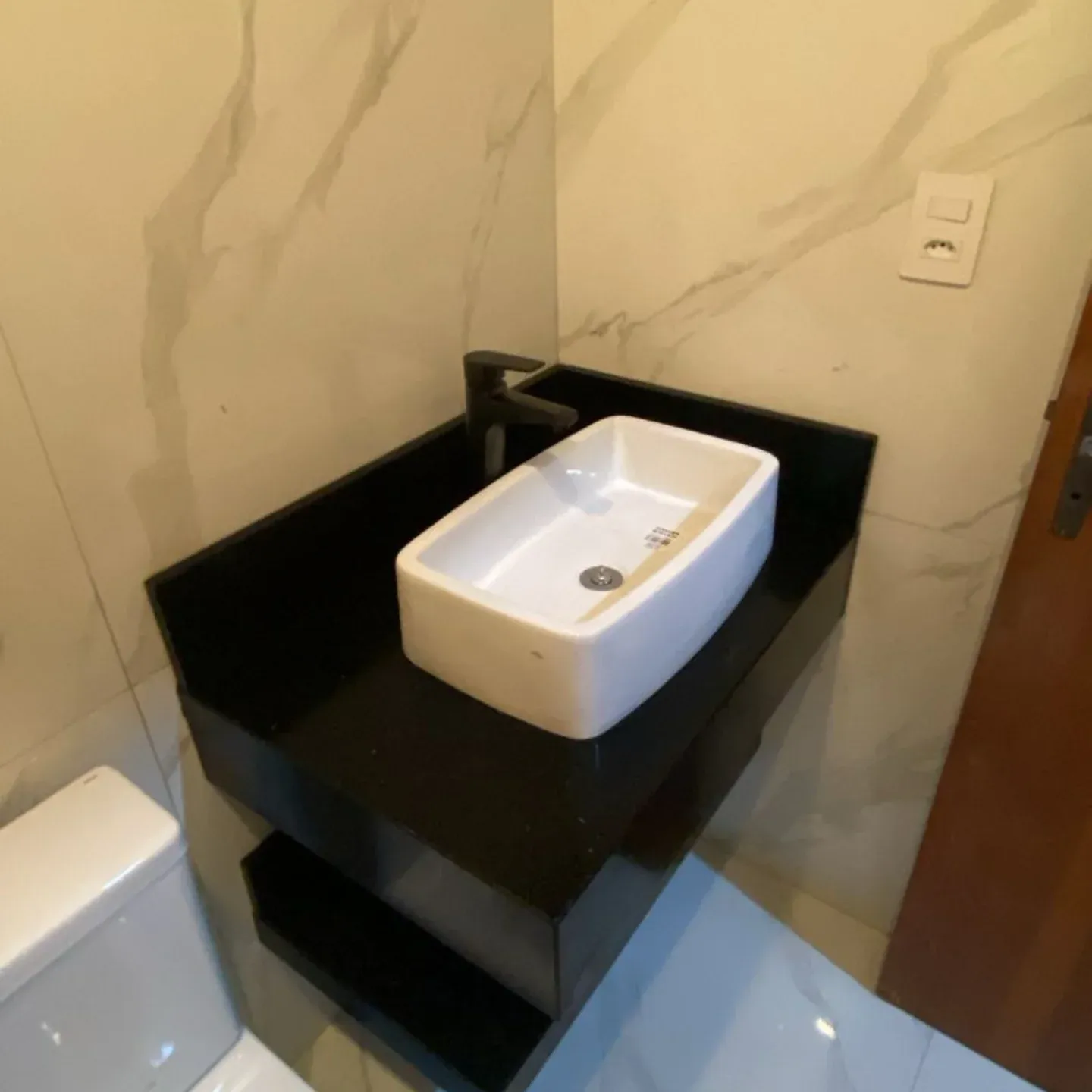 Lavabo com bancada suspensa em granito preto e nicho