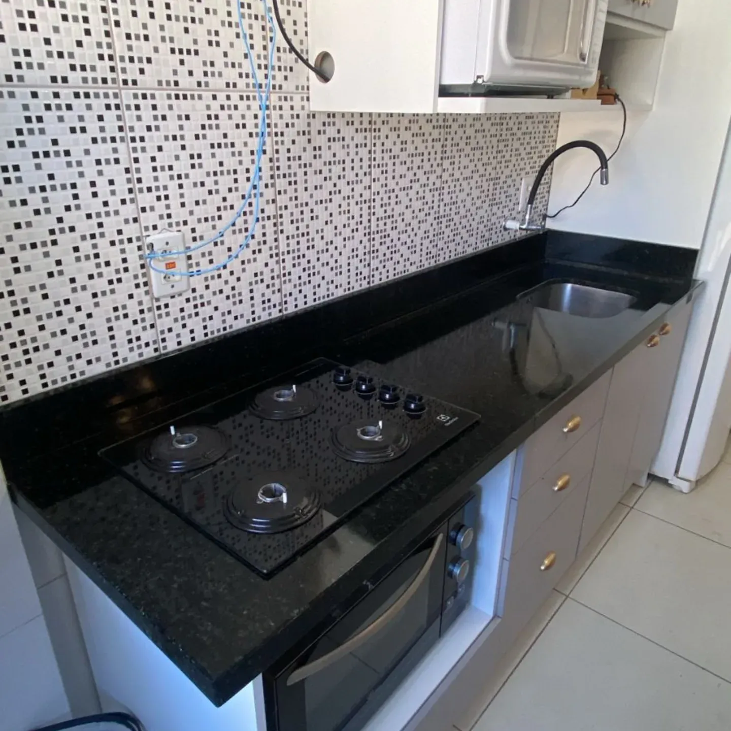 Bancada de cozinha em granito preto com cooktop e cuba