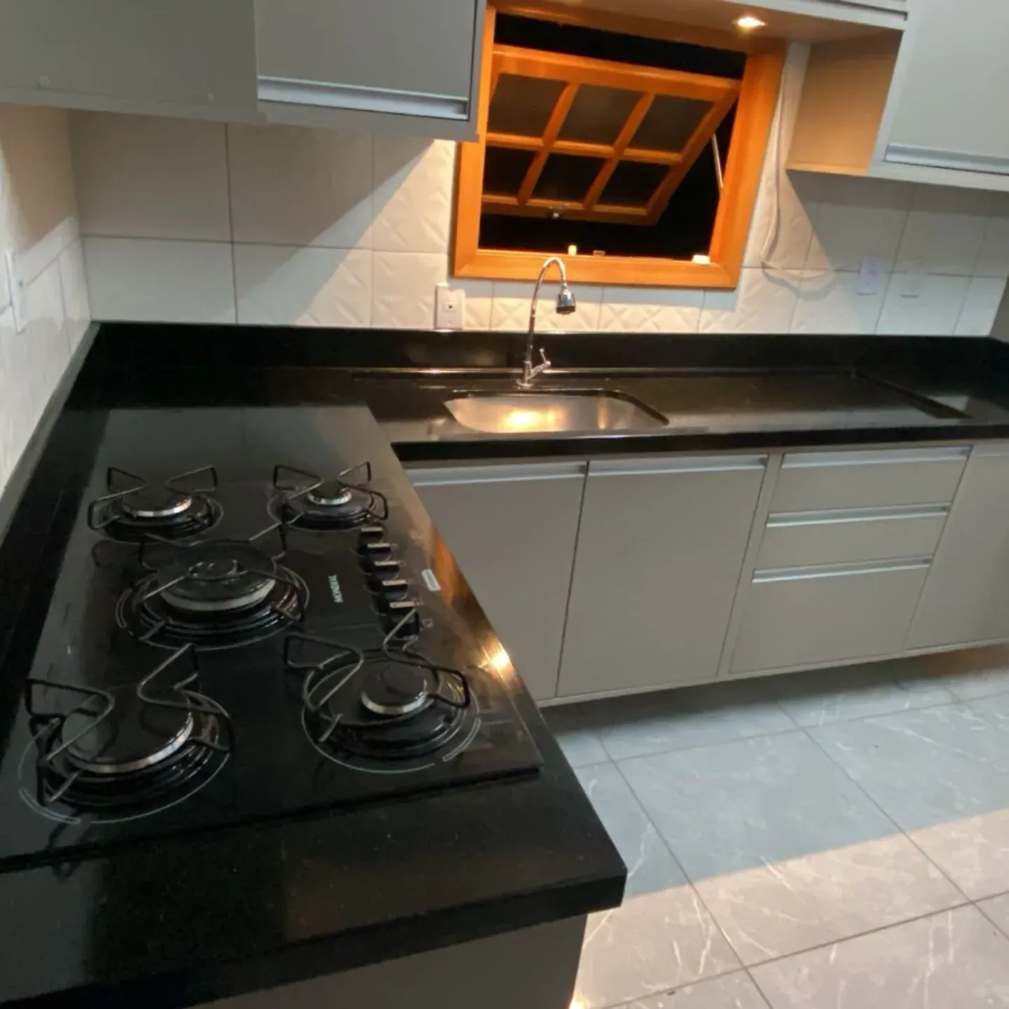 Cozinha em L com bancada de granito preto e cuba inox